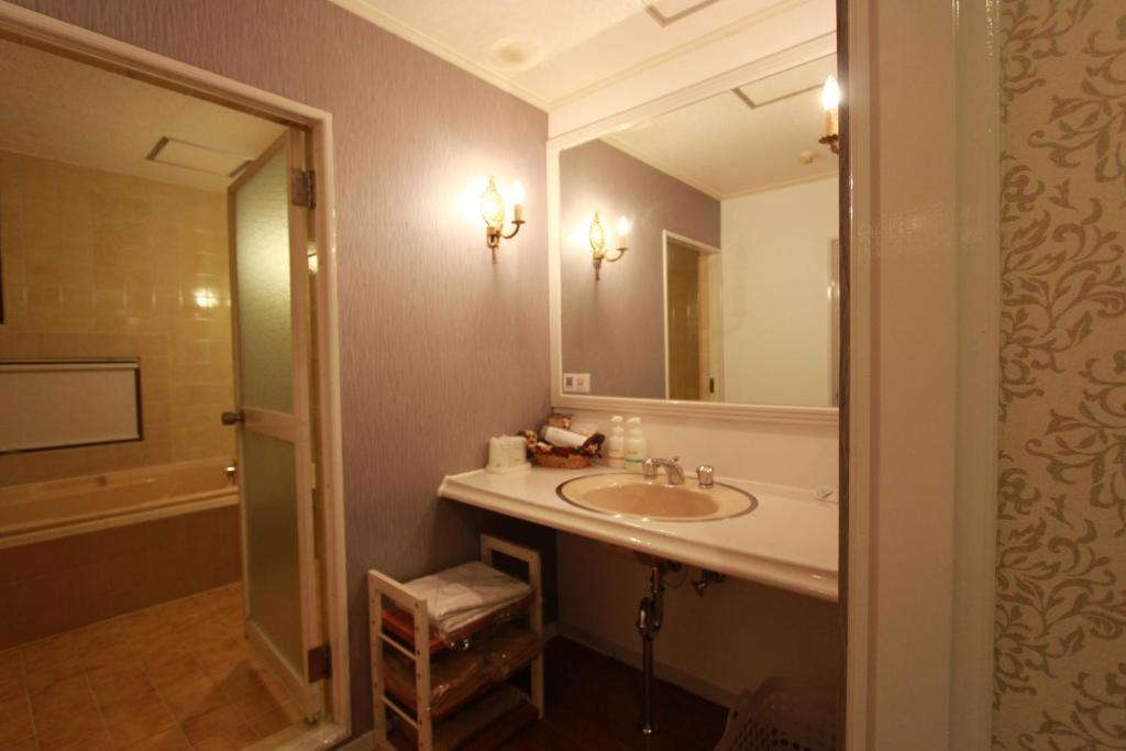 une salle de bain avec un lavabo et un grand miroir dans l'établissement Hotel JIN (Adult Only), à Hamamatsu
