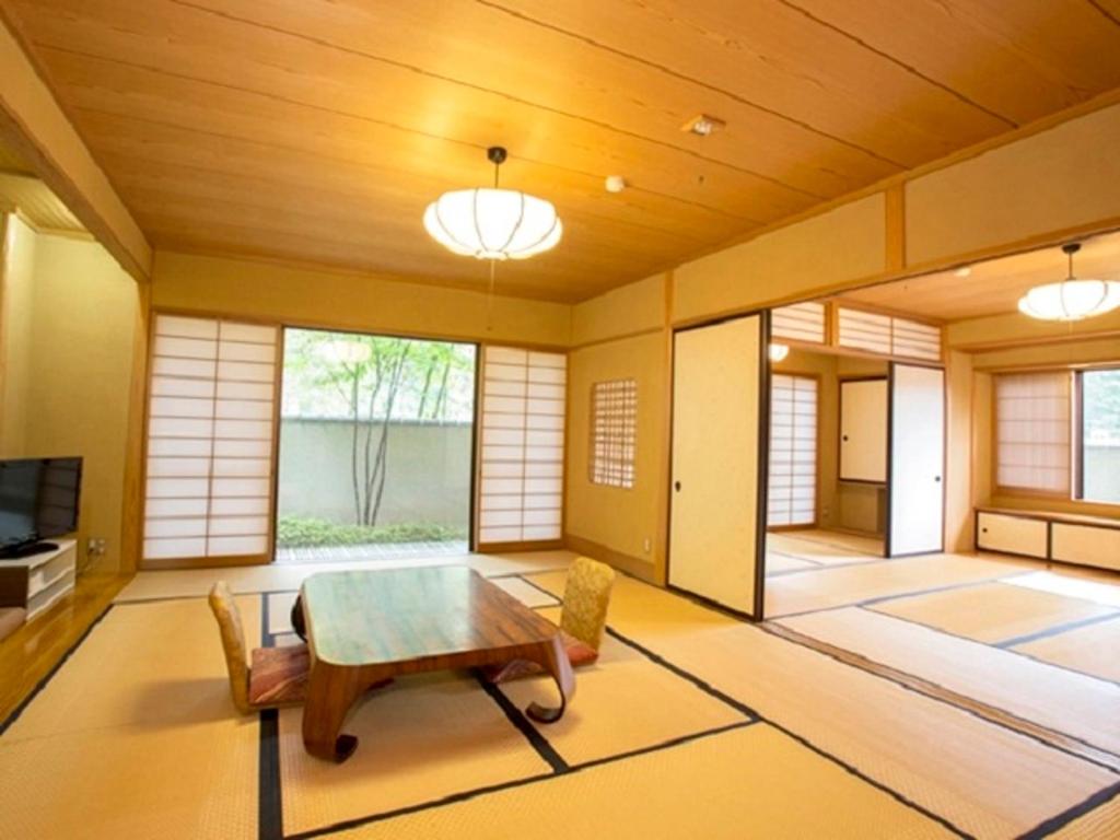 un salon avec une table et des chaises en bois dans l'établissement Izu Nagaoka Kinjokan, à Izunokuni