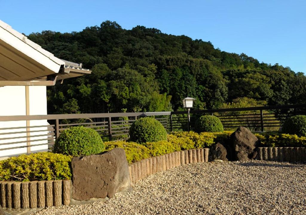 un jardin avec des rochers et des buissons en face d'une maison dans l'établissement Izu Nagaoka Kinjokan, à Izunokuni