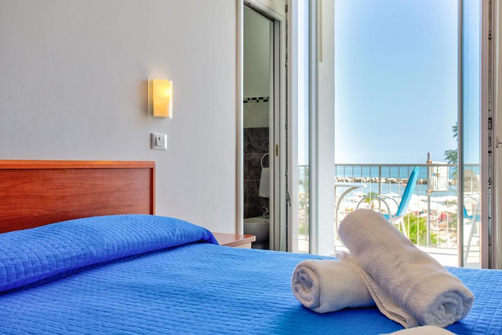 - une chambre avec un lit bleu et une serviette dans l'établissement Hotel Delle Nazioni - Valentini Family Village, à Bellaria-Igea Marina