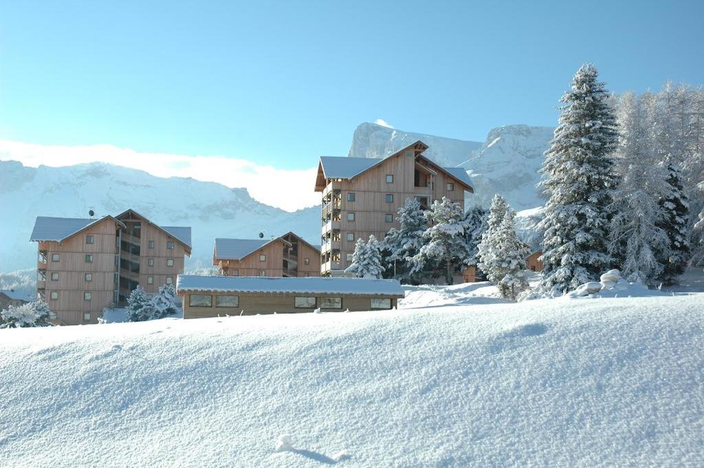 une colline enneigée avec des bâtiments en arrière-plan dans l'établissement ANCOLIE 23 Les Chalets de Super D, à Saint-Étienne-en-Dévoluy