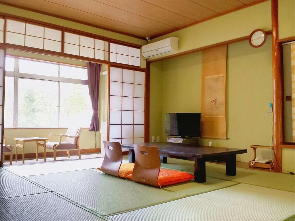 un salon avec une table et des chaises en bois dans l'établissement Hotel Yumoto, à Utsuno