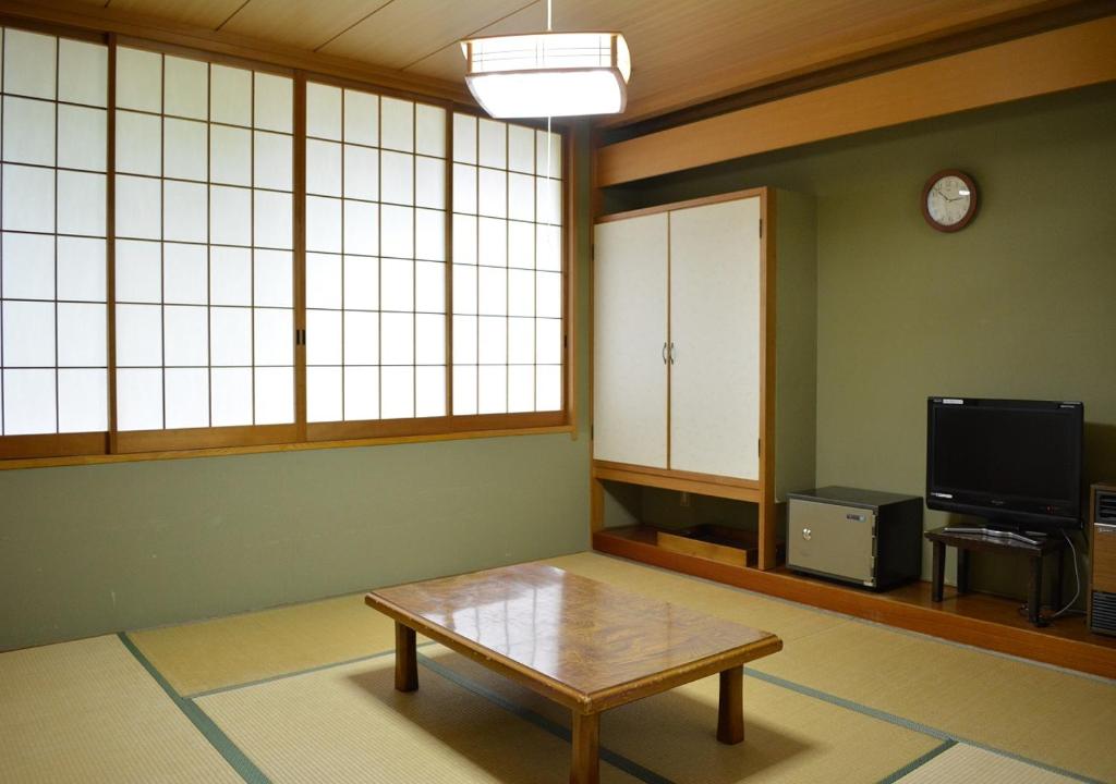 - un salon avec une table basse et une télévision dans l'établissement Itoen Hotel Oze Oigami Sanrakuso, à Numata