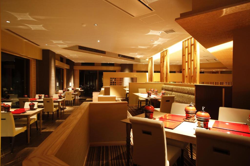 un restaurant avec des tables, des chaises blanches et un chercheur de table dans l'établissement Plaza Awajishima, à Minamiawaji