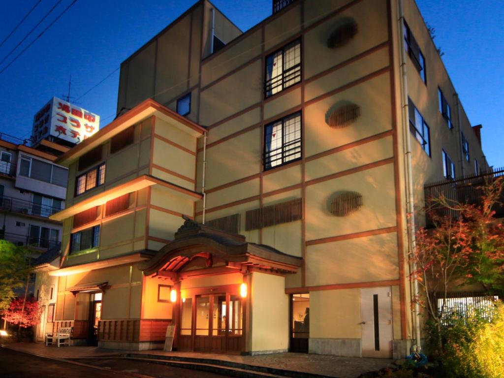 un grand bâtiment blanc éclairé dans l'établissement Hotel Tsubakino, à Yamanouchi