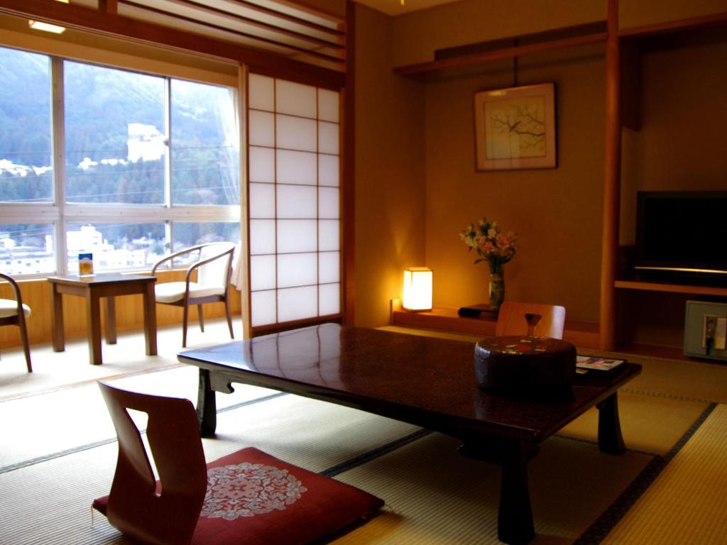 un salon avec une table et des chaises et une fenêtre dans l'établissement Gero Onsen Fugaku, à Gero