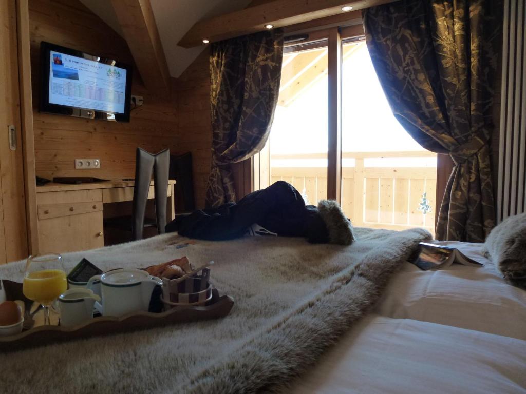 - une personne dormant sur un lit avec un plateau de nourriture dans l'établissement Hôtel Restaurant "Les Sapins" Wellness & Gourmet, à Manigod