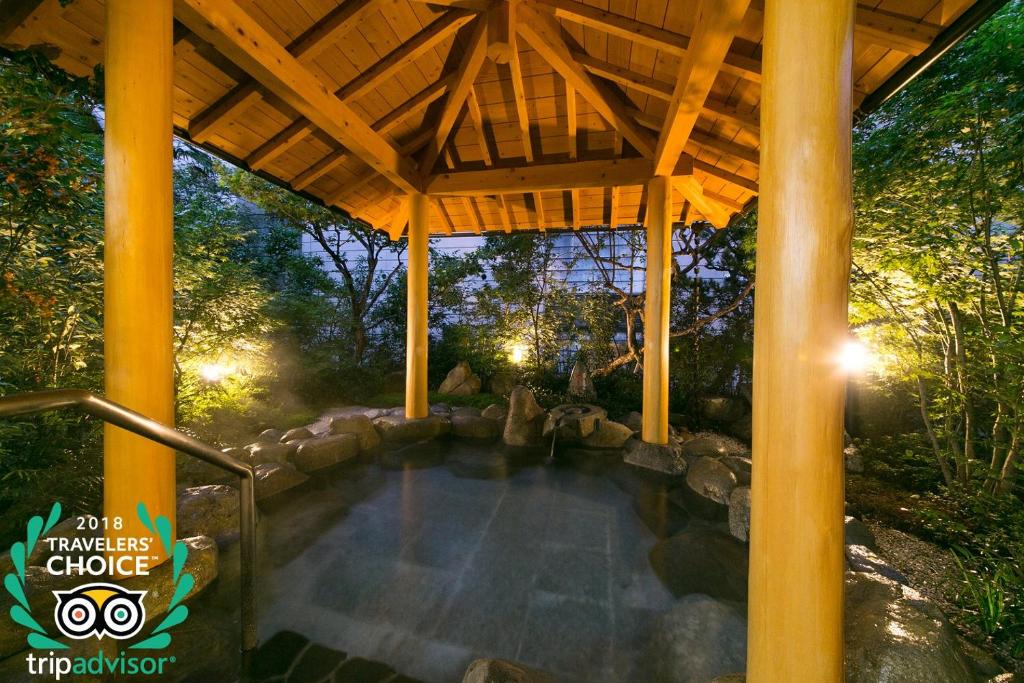 une piscine sous un toit en bois dans un jardin dans l'établissement Mutsumikan, à Gero