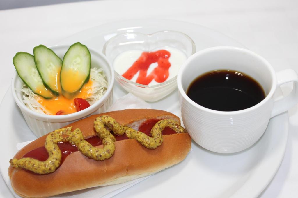 un hot dog avec un serpent sur une assiette avec une tasse de café dans l'établissement Hotel Sindbad Yamagata (Adult Only), à Higashine