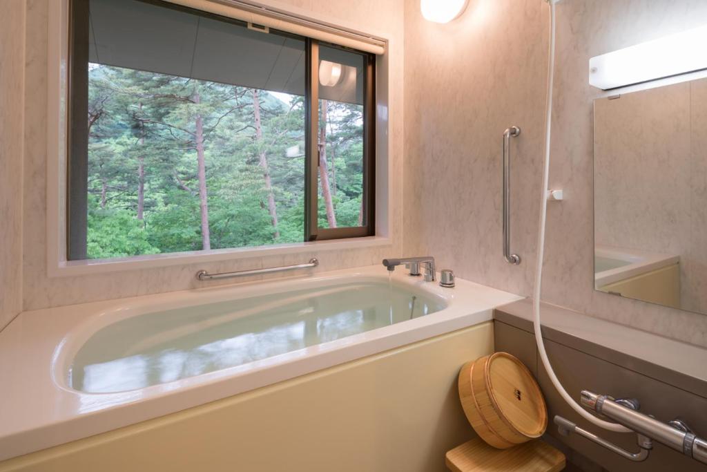 La salle de bains est pourvue d'une baignoire et d'une fenêtre. dans l'établissement Kashoen, à Hanamaki