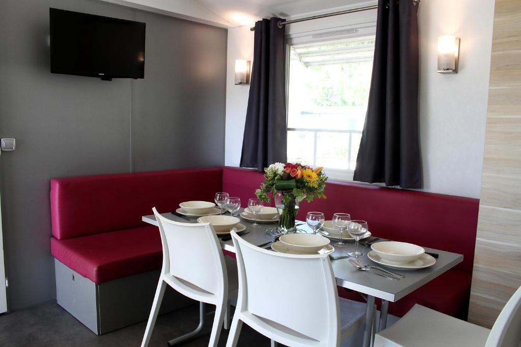 une salle à manger avec une table et un banc rouge dans l'établissement Camping Resort Les Champs Blancs, à Agde