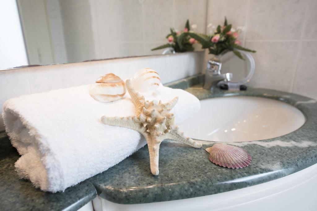 une étoile de mer posée sur un comptoir de salle de bain à côté d'un lavabo dans l'établissement Hotel Atlantic, à Bellaria-Igea Marina