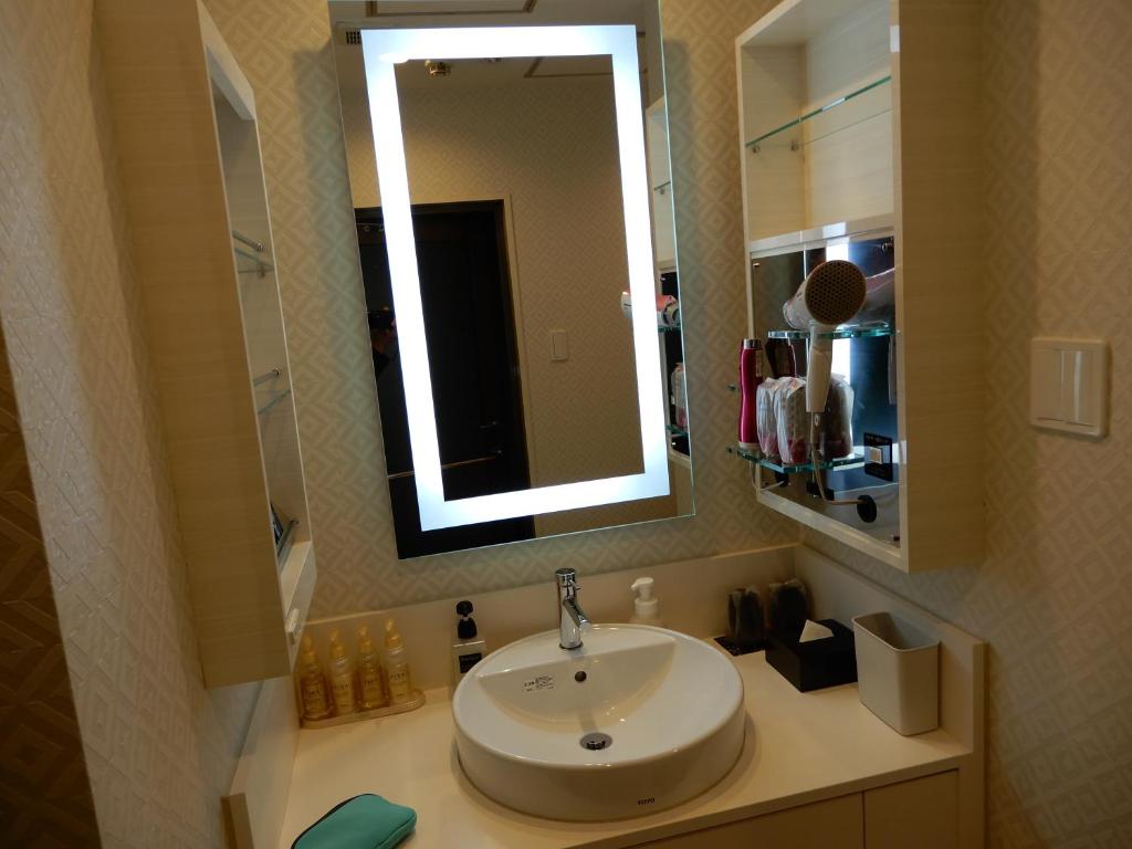 une salle de bain avec un lavabo et un miroir dans l'établissement HOTEL VERSYS (Adult Only), à Hiroshima