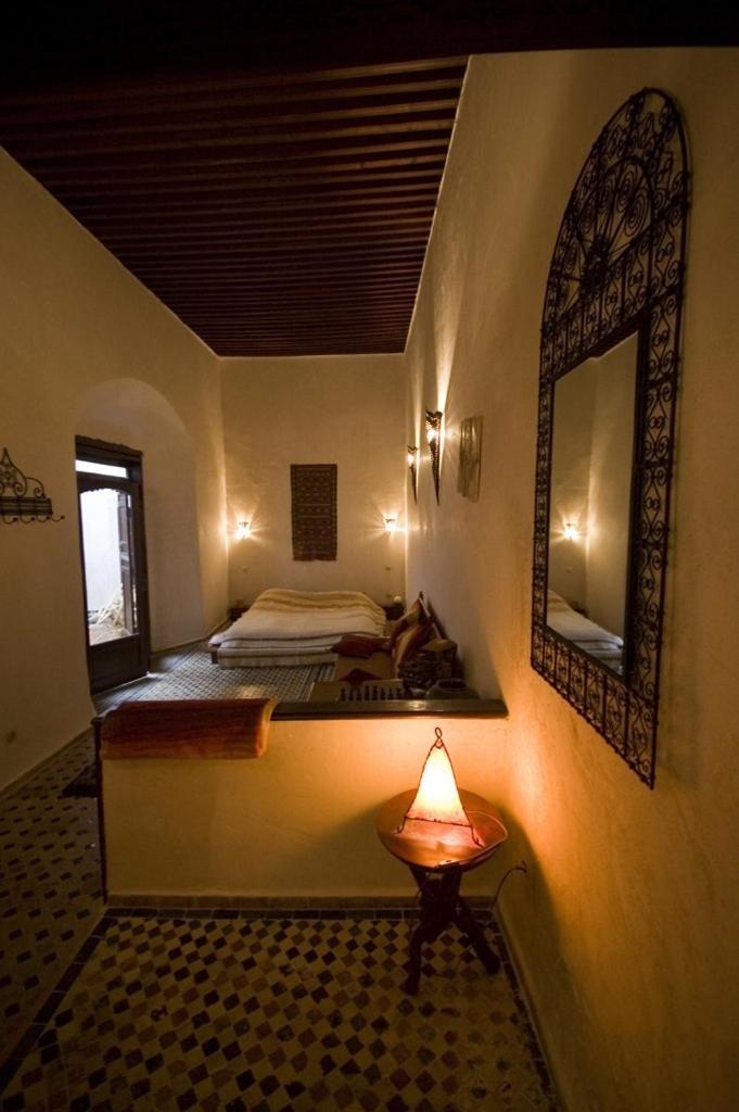 une chambre avec un lit et un miroir au mur dans l'établissement Riad Felloussia, à Meknès