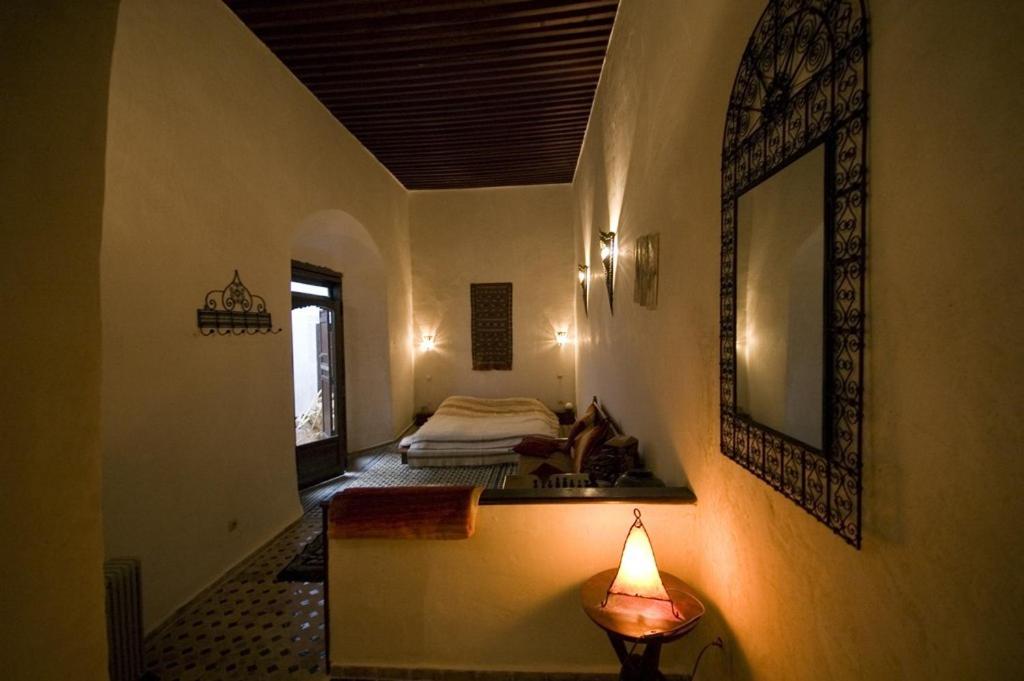 Cette chambre comprend un lit et une lampe sur un mur. dans l'établissement Riad Felloussia, à Meknès