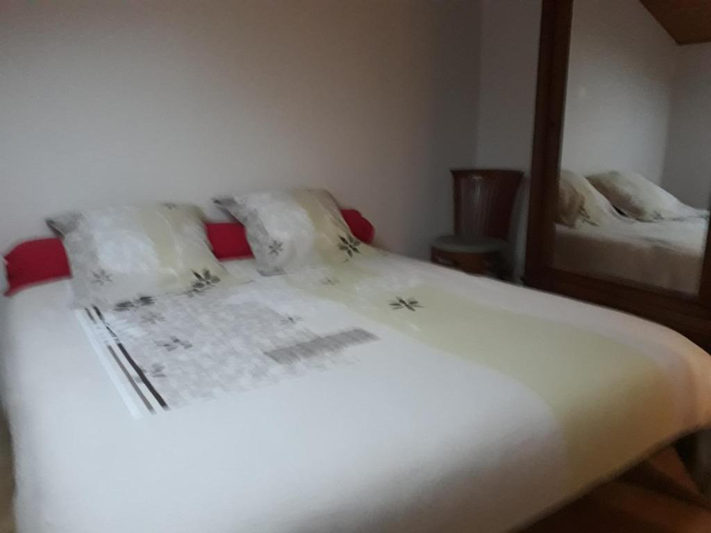 une chambre avec un lit avec des draps blancs et un miroir dans l'établissement les gites du grenit, à La Chapelle-Neuve