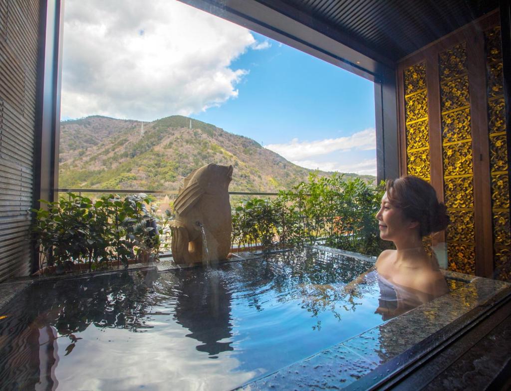 une femme dans une piscine avec un ours dans l'eau dans l'établissement Balinese onsen ryokan Hakone Airu, à Hakone