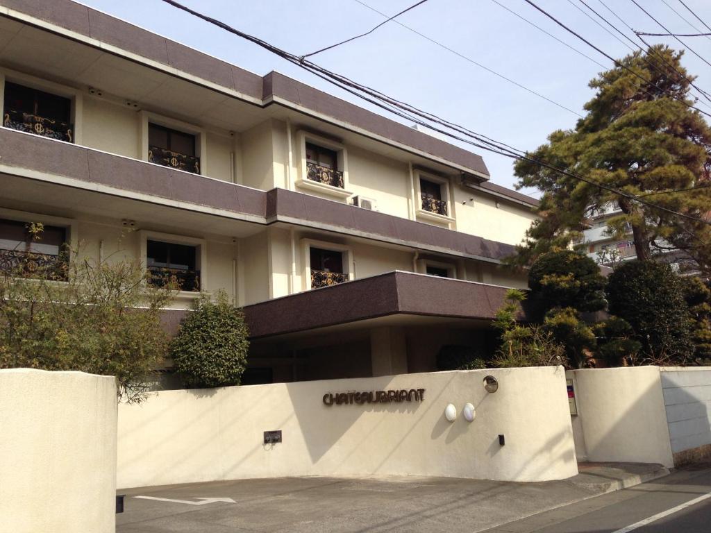 un bâtiment blanc avec une pancarte sur un mur dans l'établissement Hotel Chateau Briant (Adult only), à Saitama