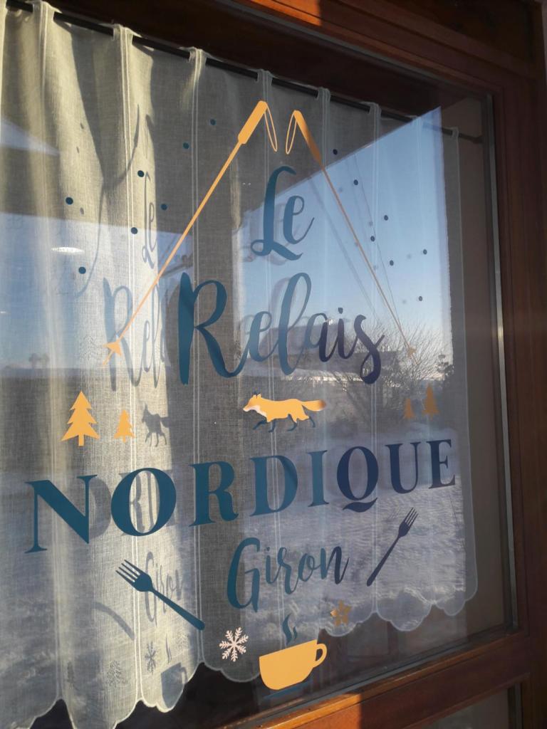 une fenêtre avec un panneau dans la fenêtre d'un restaurant dans l'établissement Le Relais Nordique, à Giron