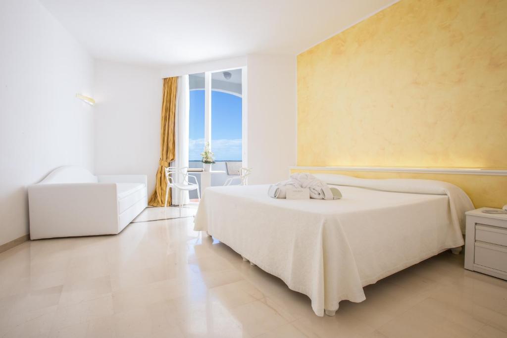 une chambre blanche avec un lit et une grande fenêtre dans l'établissement Grand Hotel Costa Brada, à Gallipoli
