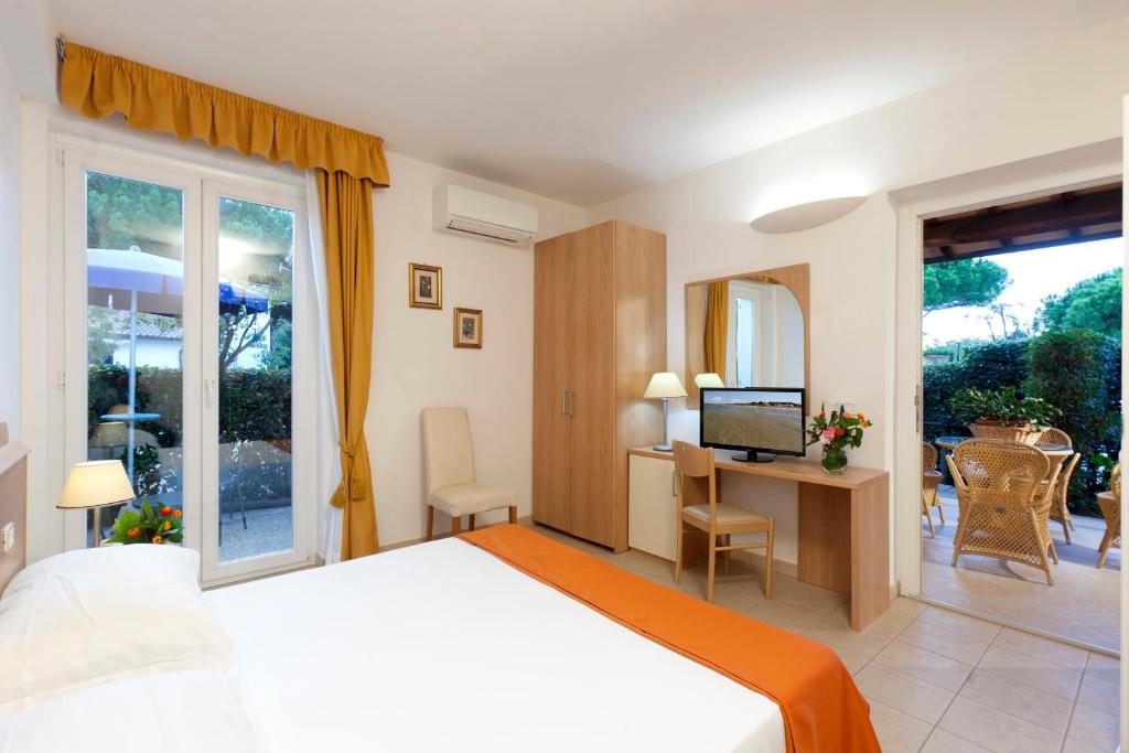 une chambre avec un lit et un bureau avec une télévision dans l'établissement Hotel Villa Smeraldo, à Orbetello