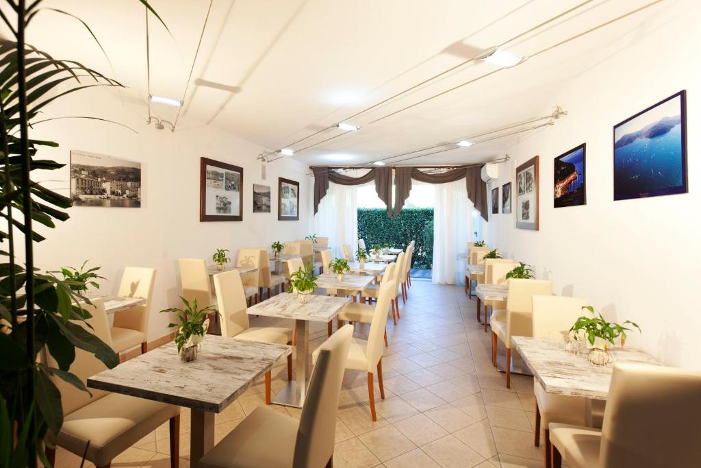 un restaurant avec des tables, des chaises et des plantes dans l'établissement Hotel Villa Smeraldo, à Orbetello