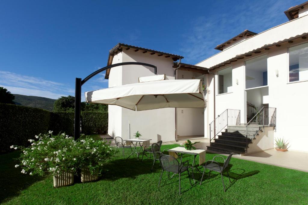 un patio avec des chaises, une table et un parasol dans l'établissement Hotel Villa Smeraldo, à Orbetello