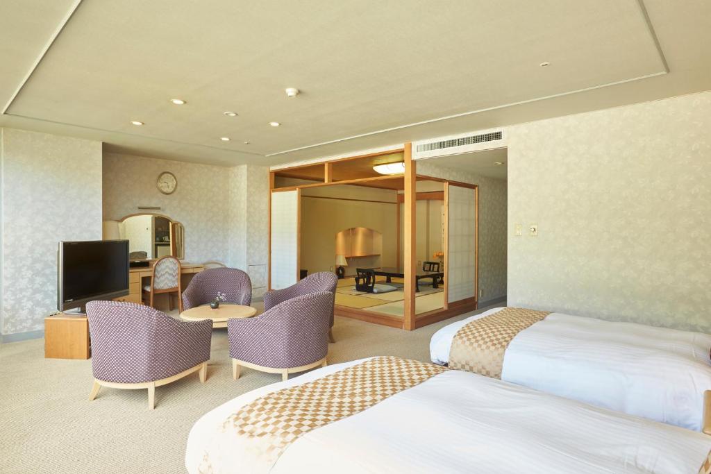 une chambre d'hôtel avec deux lits et une télévision dans l'établissement Kinugawa Onsen Sanraku, à Nikkō 37 autres photos