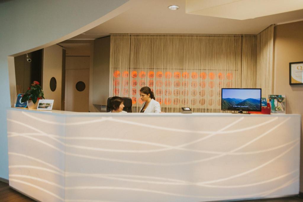 deux femmes assises à un comptoir dans un bureau dans l'établissement Hotel Arc En Ciel, à Diano Marina