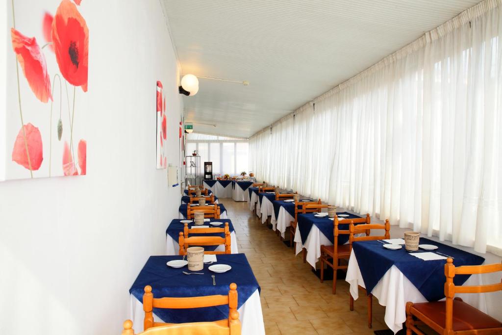 une rangée de tables dans un restaurant avec des chaises bleues et oranges dans l'établissement Hotel Lagomaggio, à Rimini