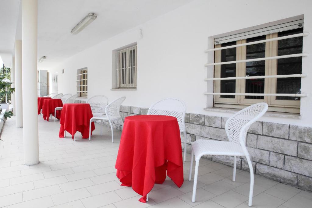 une rangée de tables et de chaises avec un tissu de table rouge dans l'établissement Hotel Lagomaggio, à Rimini