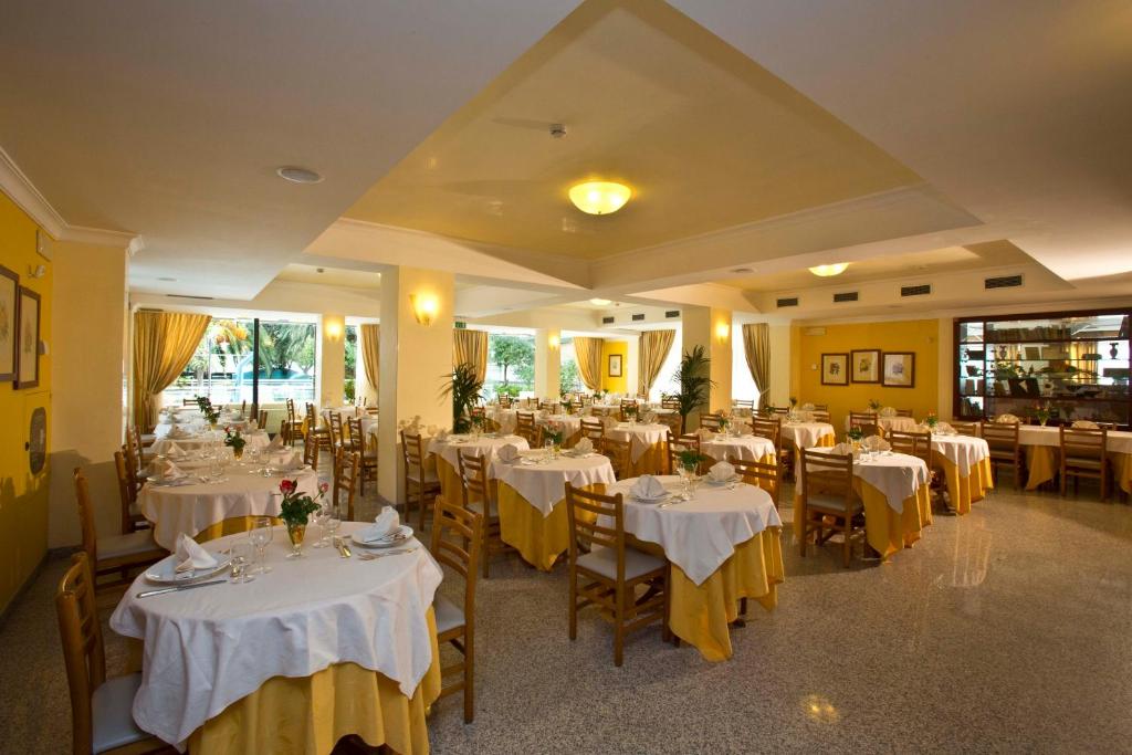 un restaurant avec des tables et des chaises avec une nappe blanche dans l'établissement Hotel Sayonara, à San Benedetto del Tronto