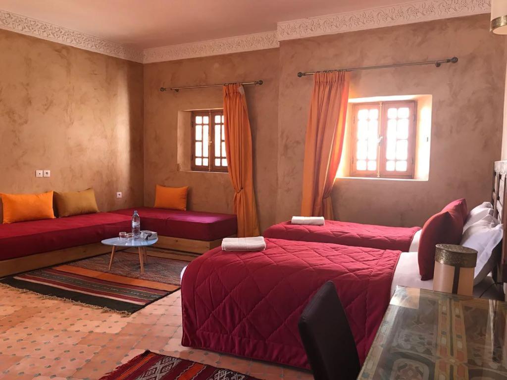 une chambre avec deux lits et une table et deux fenêtres dans l'établissement Riad jasmins & Spa, à Fès