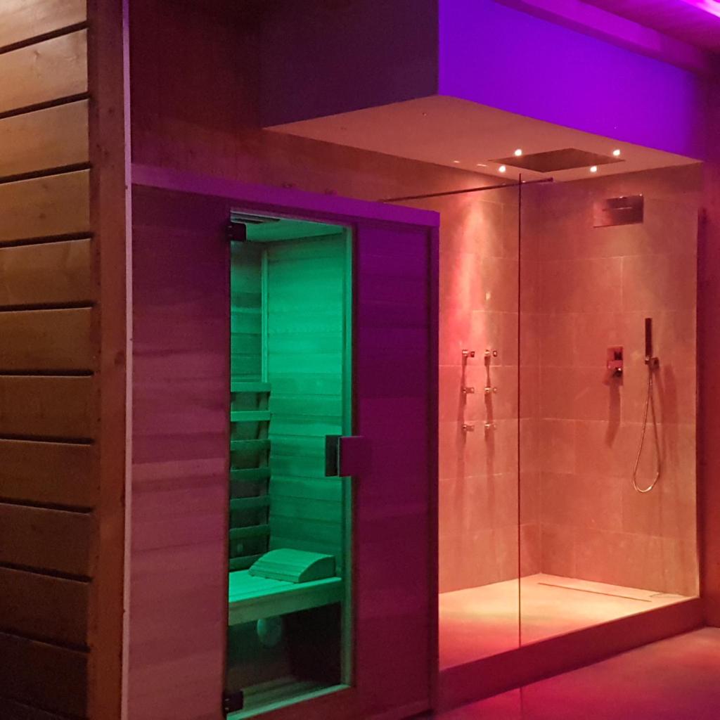 La salle de bains est pourvue d'une douche en verre avec un éclairage violet et vert. dans l'établissement Villa Edda Heated Pool, à Galatina