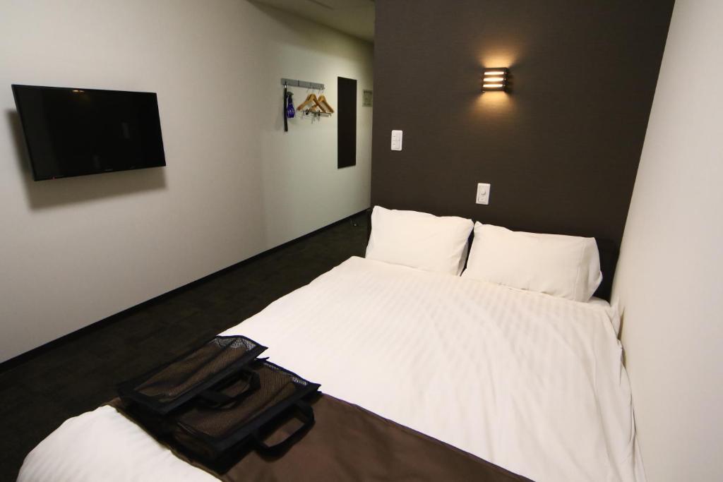 - une chambre avec un lit blanc et une télévision à écran plat dans l'établissement Teshio Onsen Yubae, à Teshio