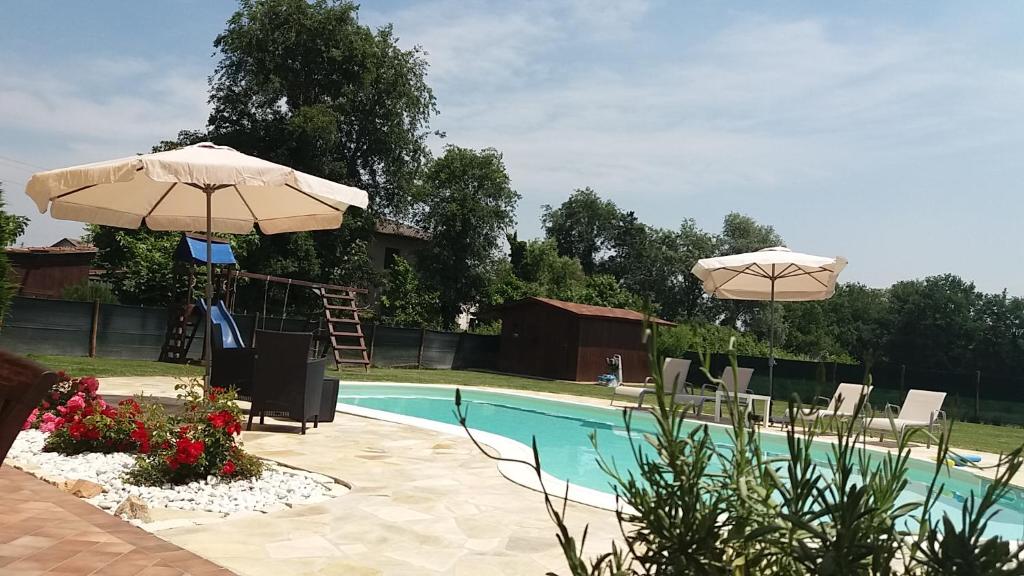 - une piscine avec un parasol, des chaises et une échelle dans l'établissement Villa Posta Vecchia, à Loreo