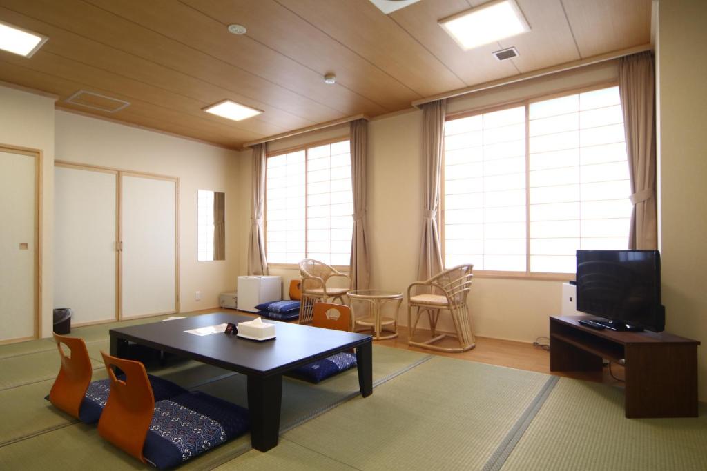 un salon avec une table et une télévision dans l'établissement Teshio Onsen Yubae, à Teshio