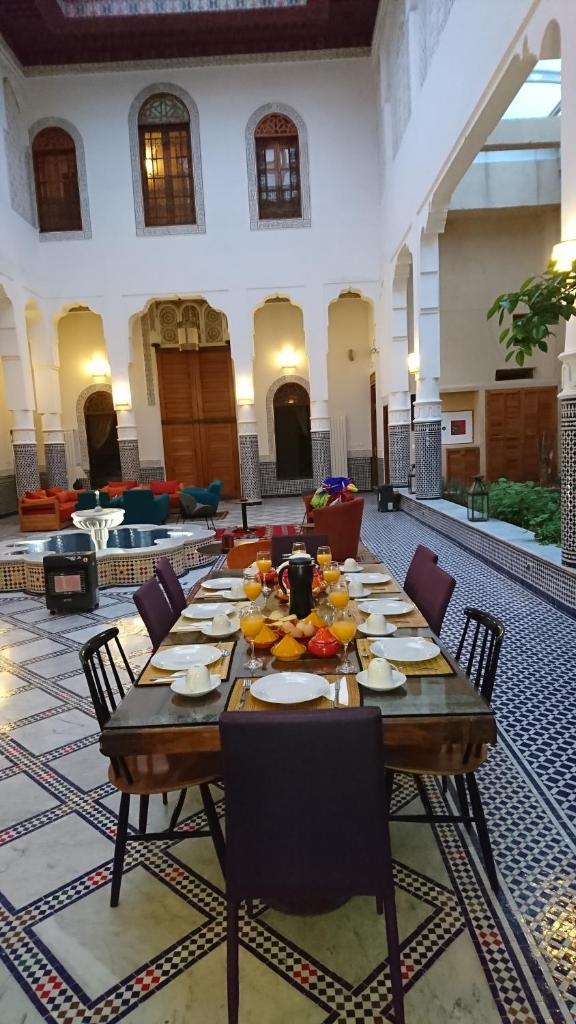 - une grande table en bois avec des chaises dans l'établissement Riad jasmins & Spa, à Fès
