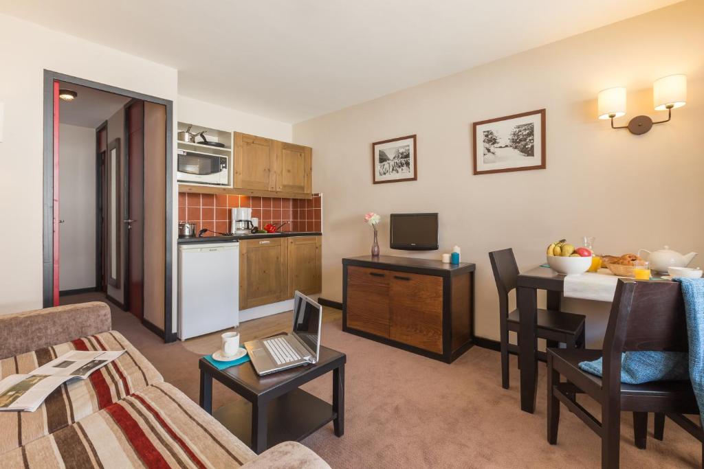 un salon avec un canapé et une table avec un ordinateur portable dans l'établissement Résidence Pierre & Vacances Le Quartz, à Belle Plagne