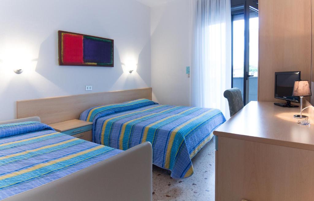 une chambre d'hôtel avec deux lits et un bureau dans l'établissement Hotel Elvia, à Lignano Sabbiadoro
