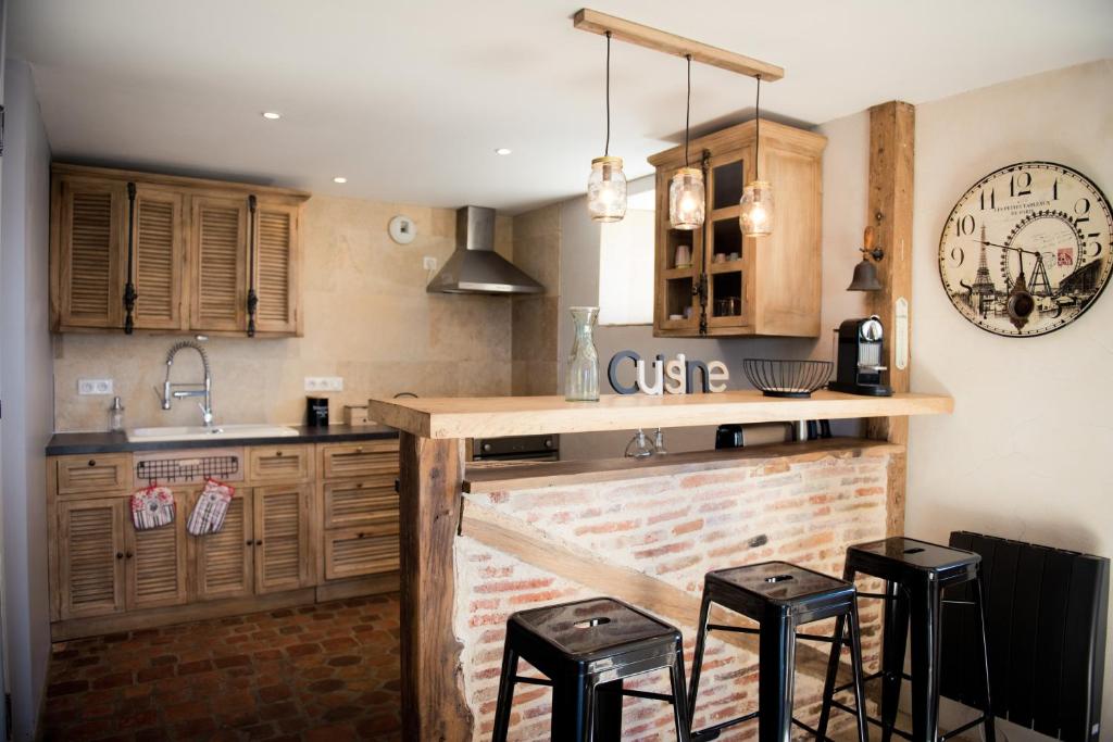 une cuisine avec des armoires en bois et un comptoir avec des tabourets dans l'établissement Gîte 8 pers du Château de Cantecor, à Alvignac