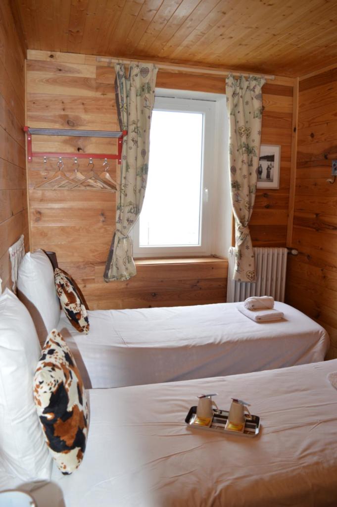une chambre avec deux lits et une fenêtre dans l'établissement Chalet Saint Bernard, à Montgenèvre