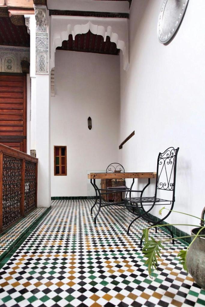 - une chambre avec une table et des chaises sur un sol en damier dans l'établissement Riad Gzira Fez, à Fès