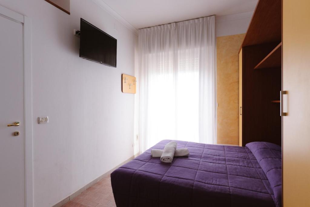 - une chambre avec un lit violet et une télévision dans l'établissement Hotel Viking, à Rimini