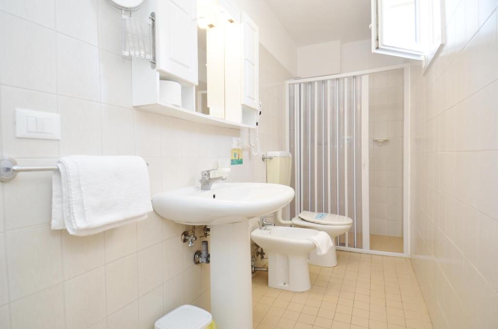 une salle de bain blanche avec un lavabo et des toilettes dans l'établissement Ute Hotel, à Lido di Jesolo