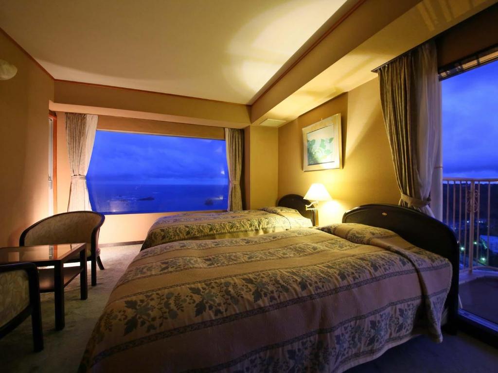une chambre d'hôtel avec un lit et une grande fenêtre dans l'établissement Shimoda View Hotel, à Shimoda