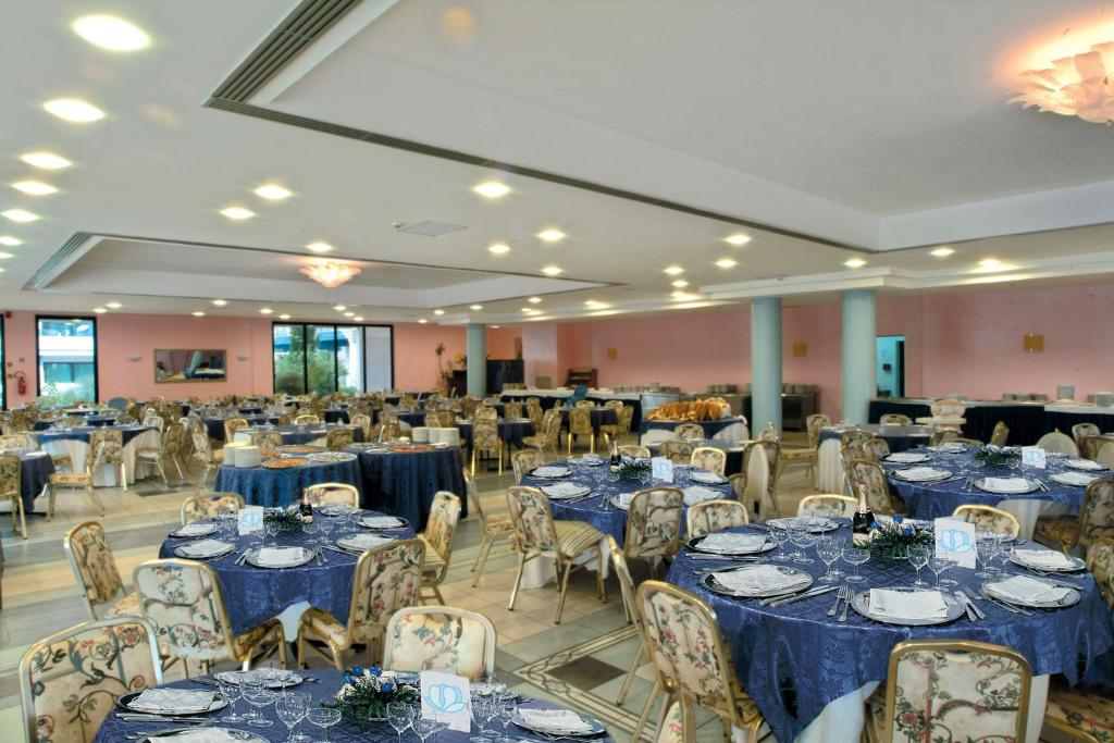 une salle de banquet avec des tables et des chaises bleues dans l'établissement Villaggio Giardini D'Oriente, à Nova Siri Marina