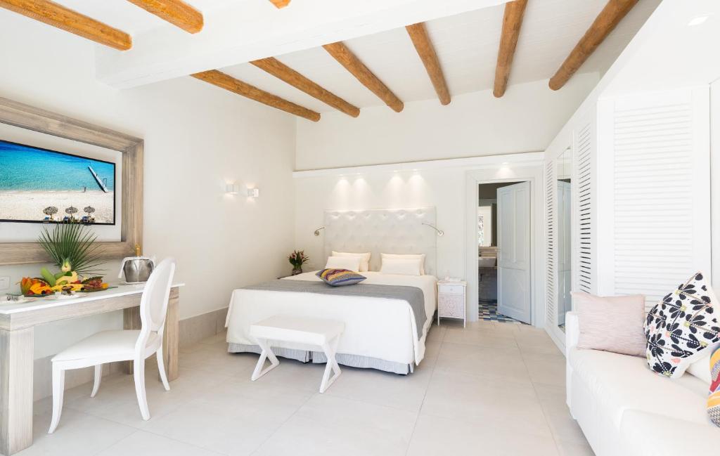 une chambre avec un lit, une table et un canapé dans l'établissement Forte Village Resort - Il Borgo, à Santa Margherita di Pula