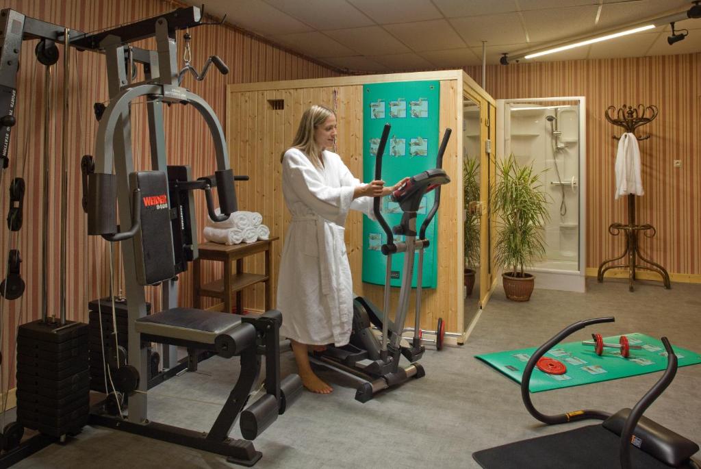 une femme debout dans une salle de sport avec un tapis de course dans l'établissement Grand Hotel de Valloire et du Galibier, à Valloire