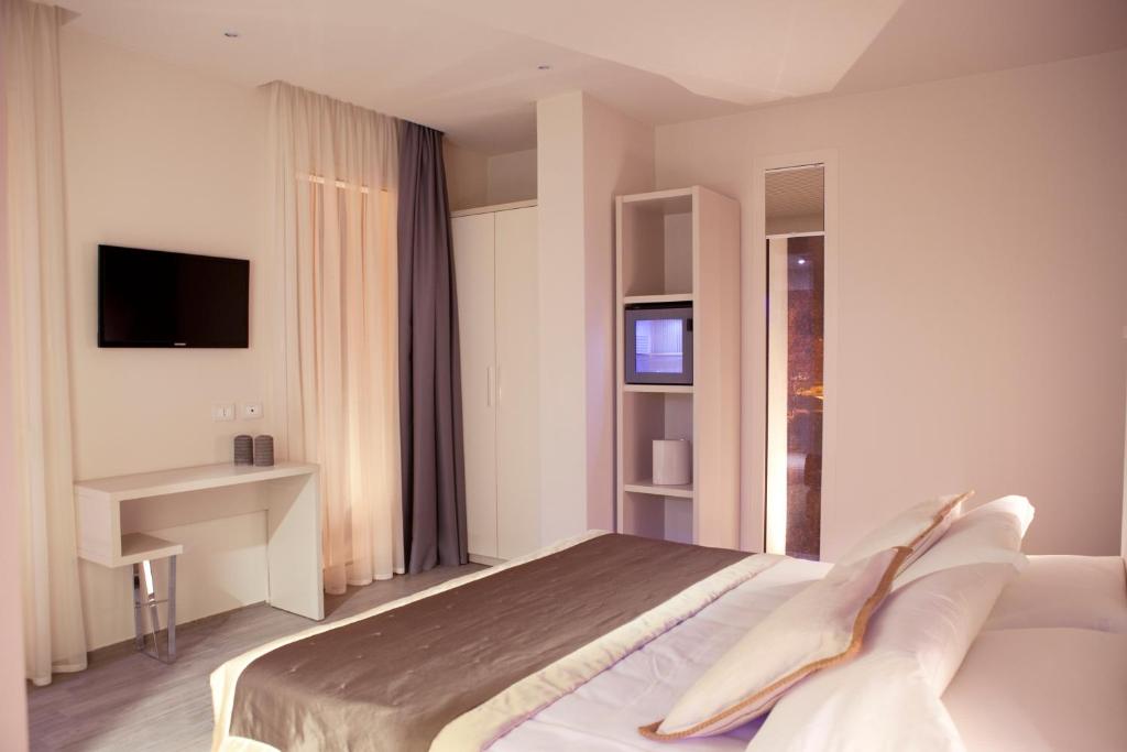 une chambre avec un lit, un bureau et une télévision dans l'établissement L'Hotel, à Rimini